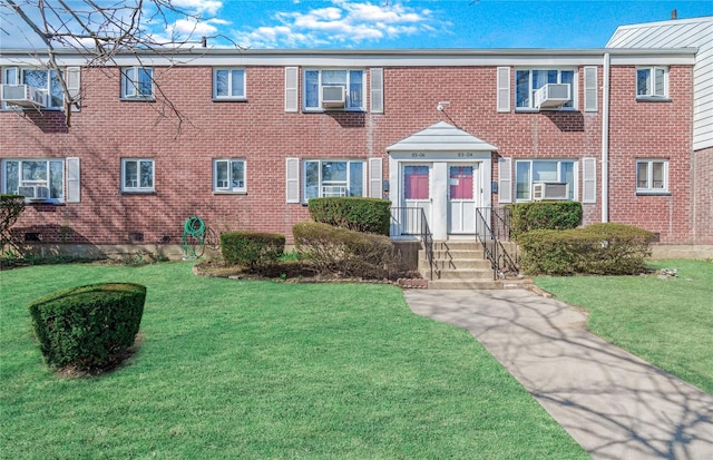view of front facade with a front yard, brick siding, and cooling unit