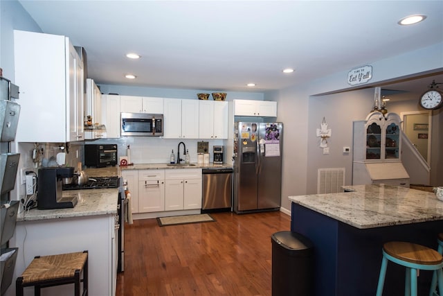 kitchen with white cabinets, visible vents, a sink, dark wood-type flooring, and appliances with stainless steel finishes