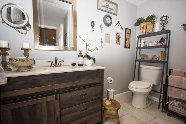 half bathroom with baseboards, vanity, tile patterned flooring, and toilet
