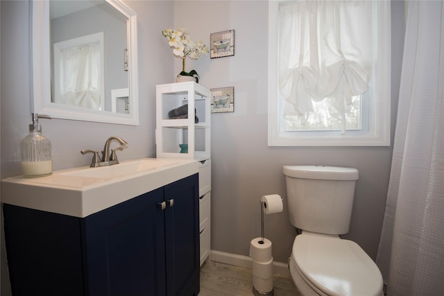 bathroom featuring baseboards, toilet, and vanity