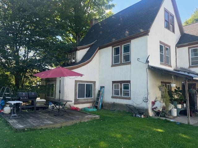 back of house with a patio, a shingled roof, stucco siding, and a lawn