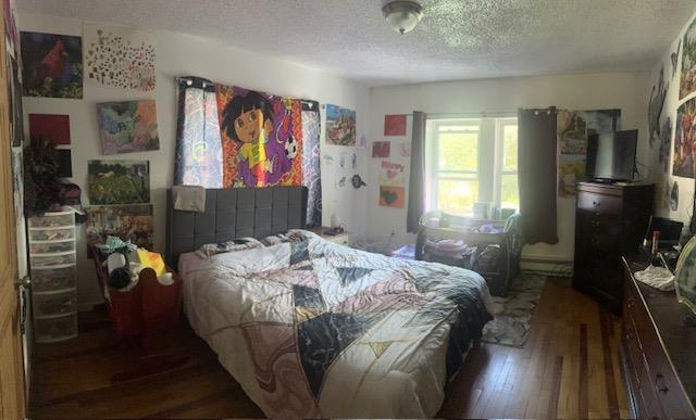bedroom with hardwood / wood-style floors and a textured ceiling