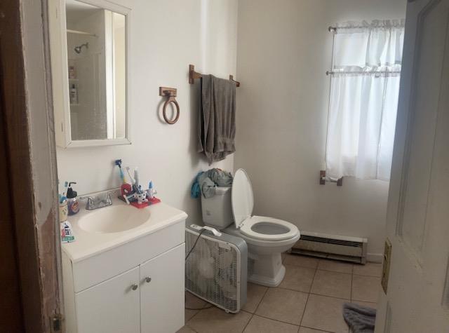 full bath featuring vanity, tile patterned flooring, toilet, a shower, and a baseboard radiator
