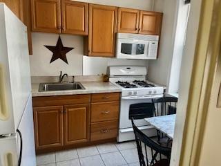 63-61 99th St Unit A4, Rego Park, NY 11374 - kitchen featuring white appliances, a sink, light countertops, and brown cabinets