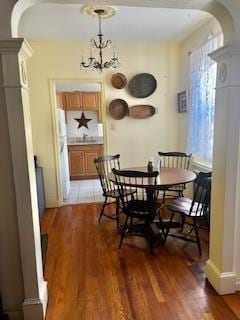 63-61 99th St Unit A4, Rego Park, NY 11374 - dining space with arched walkways, light wood-style flooring, decorative columns, and a chandelier