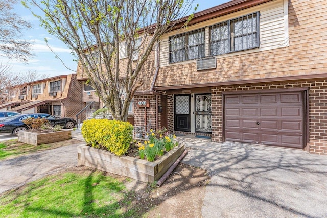 multi unit property featuring an attached garage, a shingled roof, aphalt driveway, and brick siding