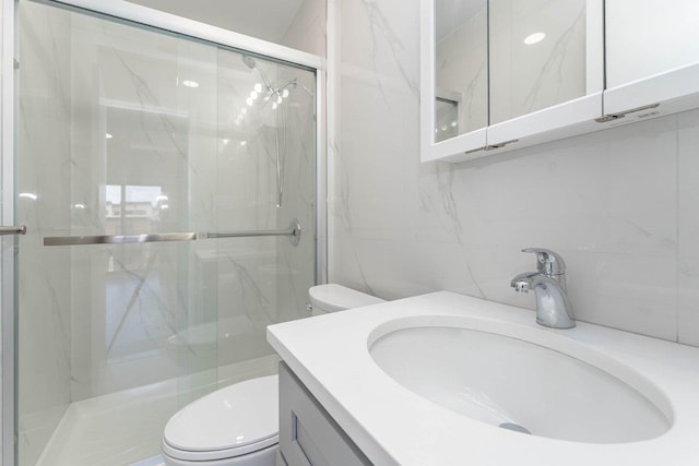 full bath featuring vanity, a marble finish shower, and toilet