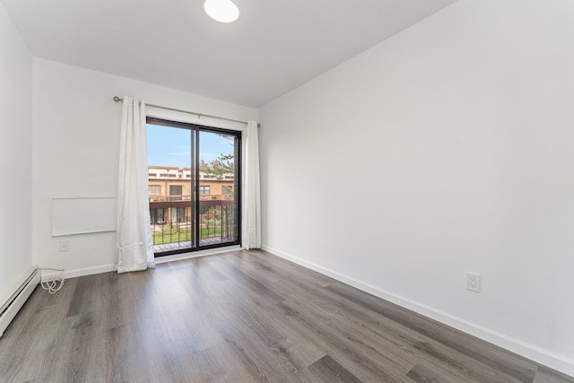 spare room with wood finished floors, a baseboard heating unit, and baseboards
