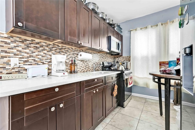 kitchen with light countertops, decorative backsplash, light tile patterned floors, and stainless steel appliances