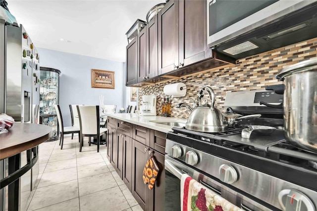 kitchen with light countertops, stainless steel gas range, dark brown cabinetry, and decorative backsplash