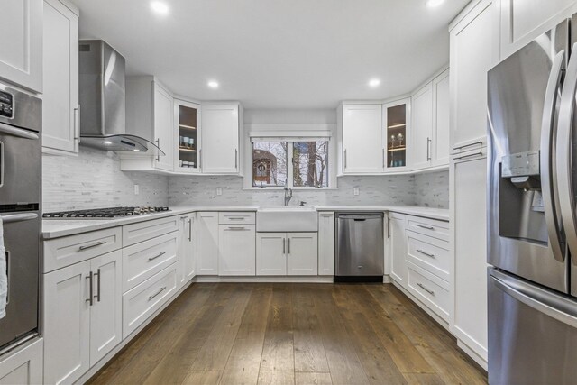 187 Jackson Ave, Pelham, NY 10803 - kitchen with wall chimney range hood, white cabinetry, light countertops, appliances with stainless steel finishes, and dark wood-type flooring