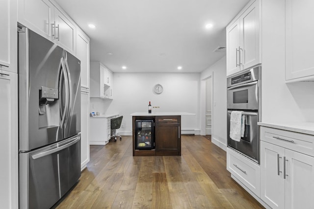 187 Jackson Ave, Pelham, NY 10803 - kitchen with recessed lighting, wine cooler, wood-type flooring, appliances with stainless steel finishes, and white cabinetry