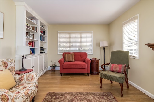 sitting room featuring light wood-style flooring, baseboard heating, and baseboards
