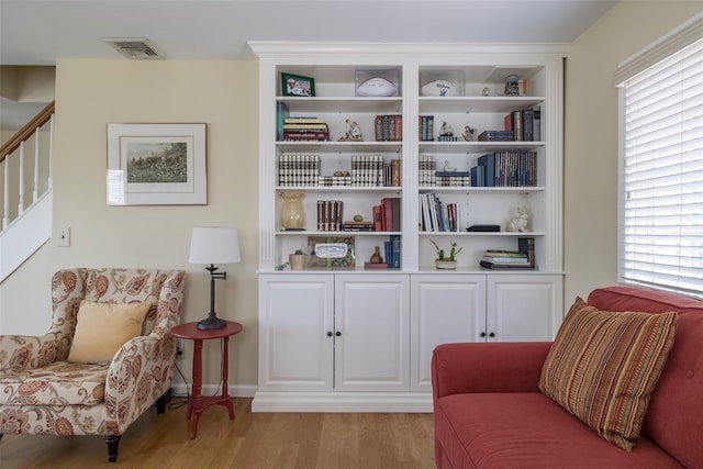 living area featuring light wood-style floors, visible vents, and stairs