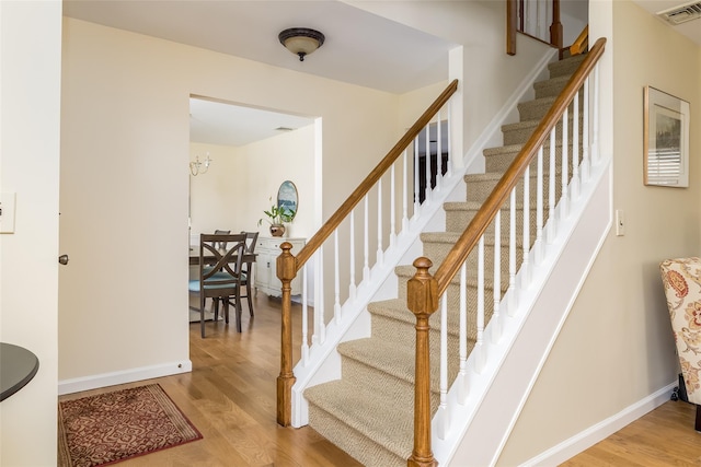 stairway with wood finished floors, visible vents, and baseboards