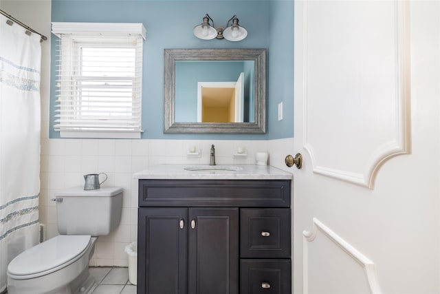 full bath with tile patterned flooring, wainscoting, tile walls, toilet, and vanity