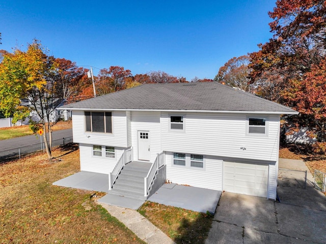 rear view of property featuring a patio area, an attached garage, fence, and a shingled roof
