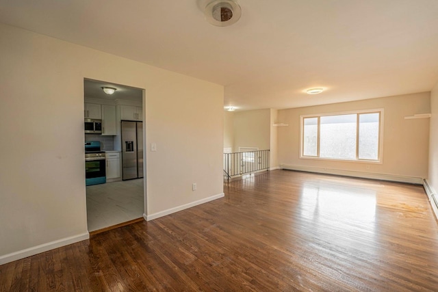 spare room featuring a baseboard radiator, wood finished floors, and baseboards