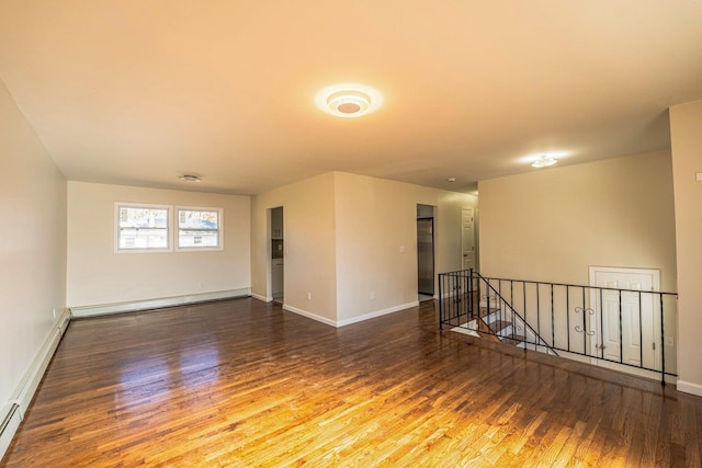 spare room with baseboards, a baseboard heating unit, and wood finished floors