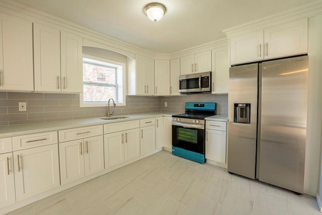 kitchen featuring stainless steel appliances, light countertops, a sink, and decorative backsplash