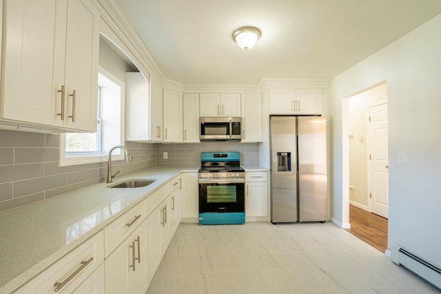 kitchen with white cabinets, appliances with stainless steel finishes, a sink, a baseboard radiator, and decorative backsplash