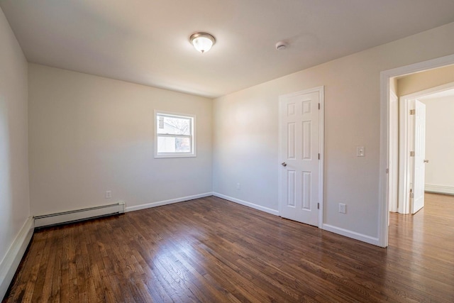 spare room featuring dark wood-type flooring, a baseboard radiator, and baseboards
