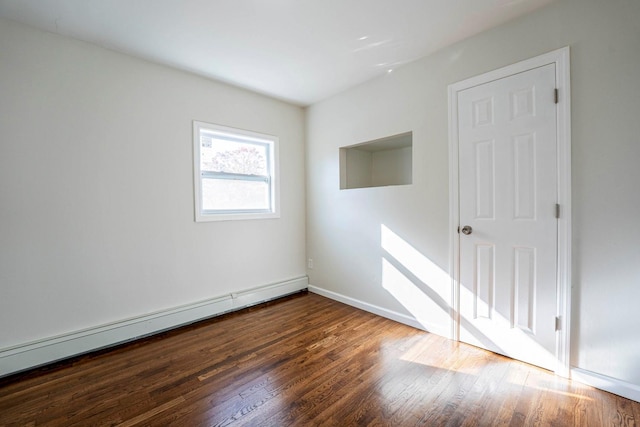 unfurnished room featuring baseboards, a baseboard heating unit, and wood finished floors