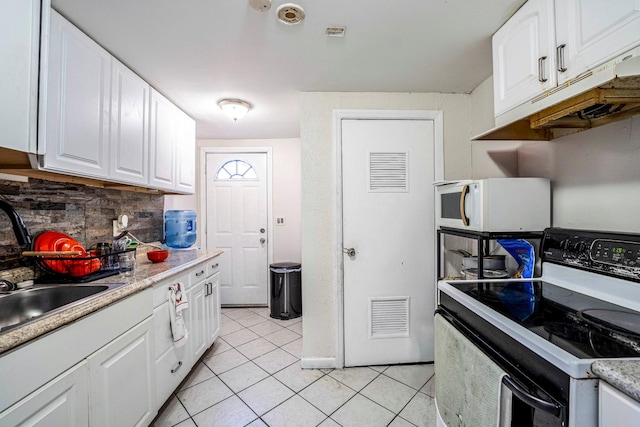 kitchen featuring white cabinets, white microwave, electric range, and light tile patterned floors