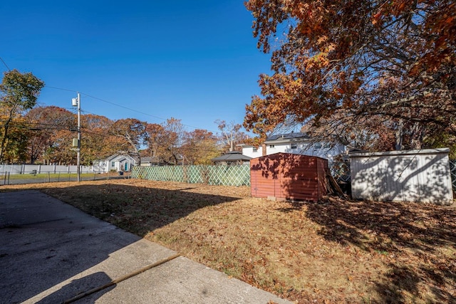 view of yard featuring a shed, an outdoor structure, and fence