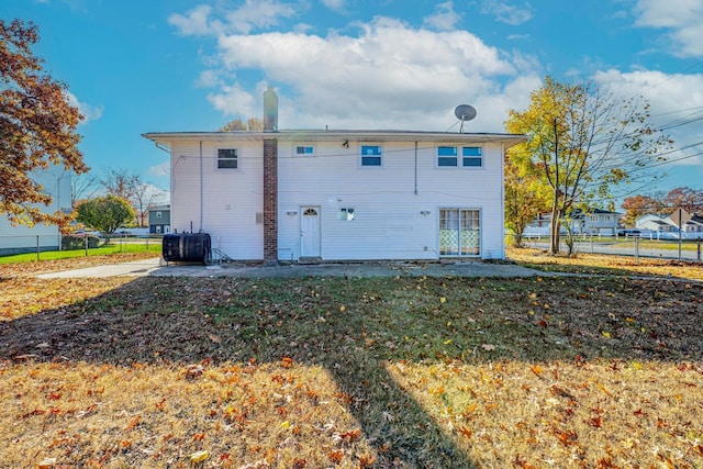 back of property with a yard, fence, and a chimney