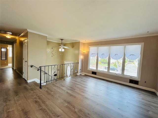 spare room with visible vents, baseboards, crown molding, and wood finished floors