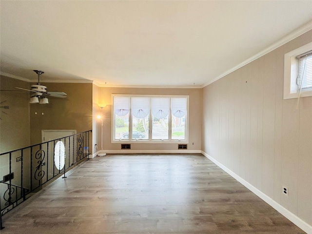 empty room with crown molding, wood finished floors, a ceiling fan, and visible vents