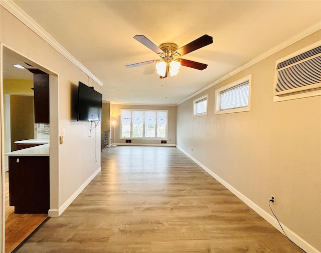 spare room with baseboards, ceiling fan, light wood-style floors, crown molding, and a wall unit AC