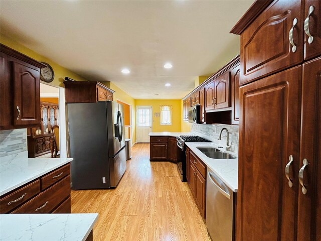 kitchen with light wood-style flooring, recessed lighting, appliances with stainless steel finishes, a sink, and decorative backsplash