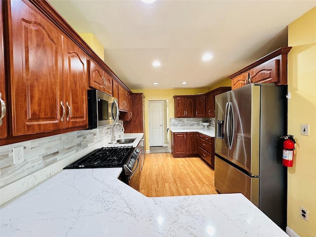 kitchen with tasteful backsplash, light wood-type flooring, recessed lighting, stainless steel appliances, and a sink