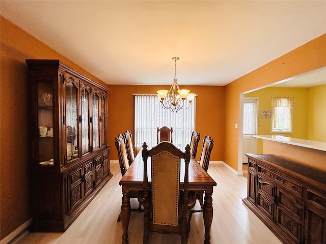 dining area with baseboards, an inviting chandelier, and light wood-style floors