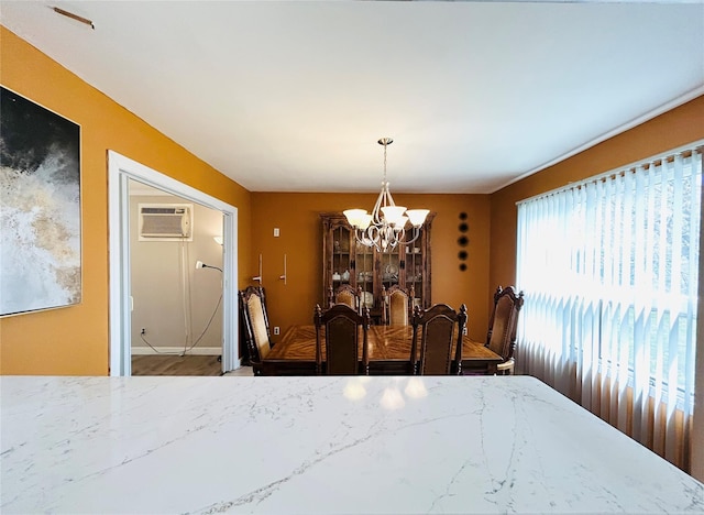 dining room featuring a chandelier and a wall unit AC