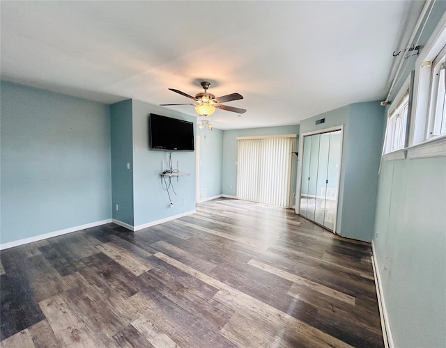 unfurnished living room featuring dark wood-style flooring, baseboards, a ceiling fan, and a healthy amount of sunlight