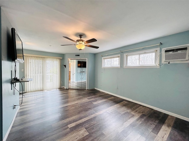 interior space featuring wood finished floors, baseboards, a wall unit AC, and ceiling fan