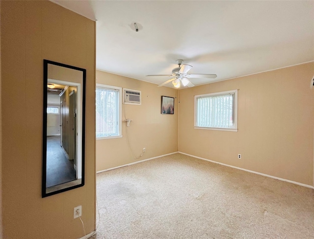 empty room with a wall mounted air conditioner, carpet flooring, baseboards, and ceiling fan