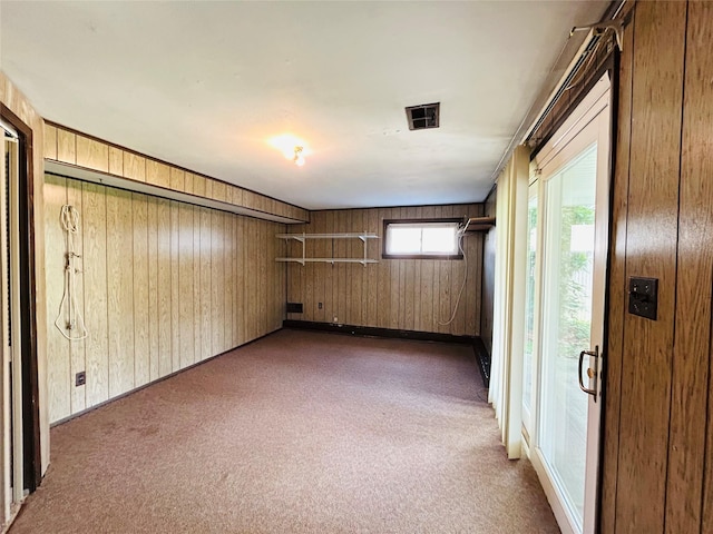spare room with wooden walls, visible vents, and carpet floors