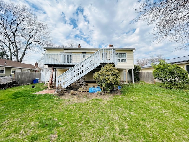 rear view of property with a deck, a lawn, fence, and stairway