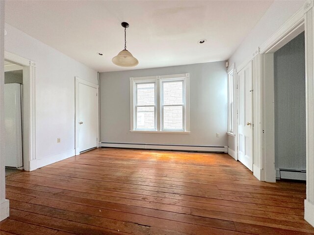 empty room with recessed lighting, baseboard heating, hardwood / wood-style flooring, and baseboards