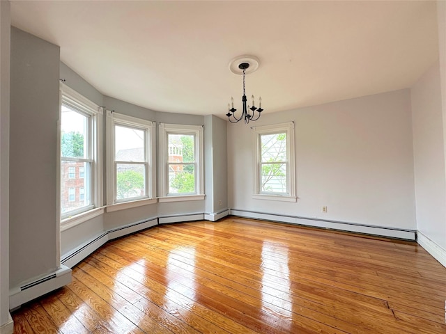 spare room with a baseboard radiator, baseboards, a notable chandelier, and light wood-style floors