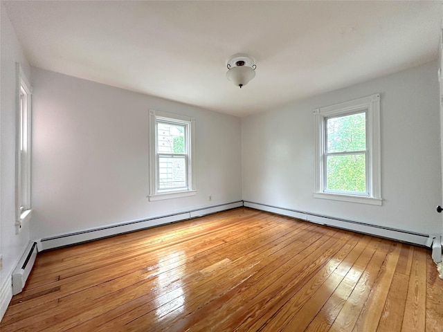 unfurnished room with baseboard heating and light wood-type flooring