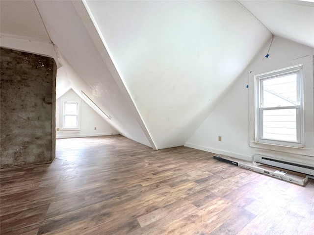 additional living space featuring baseboards, a baseboard heating unit, wood finished floors, and lofted ceiling