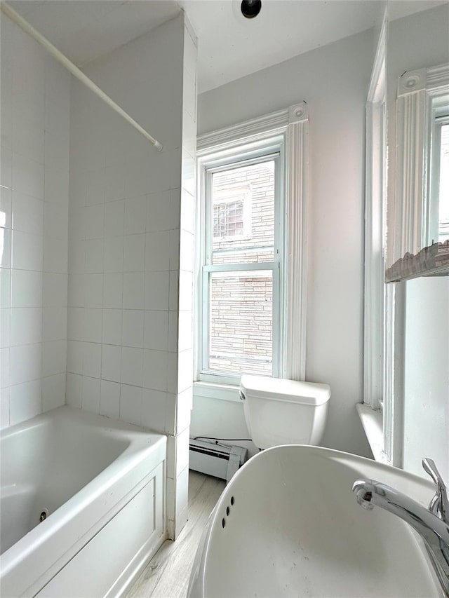 full bath featuring toilet, wood finished floors, a baseboard heating unit, and plenty of natural light