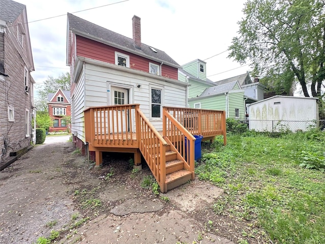 back of property with fence, a wooden deck, and a chimney
