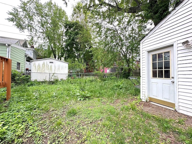 view of yard with a storage shed, an outbuilding, and fence