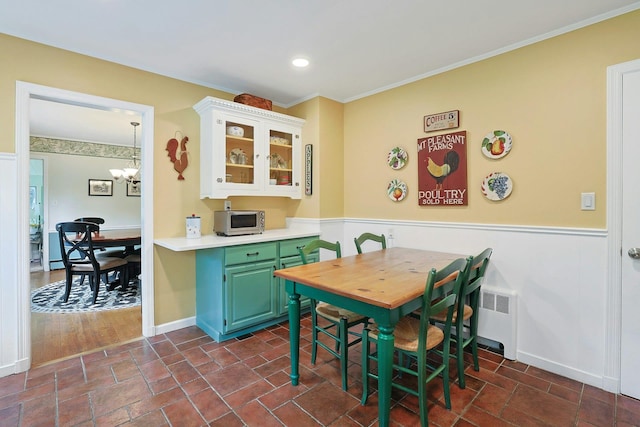 12 Heath Rd, Valhalla, NY 10595 - dining area featuring a wainscoted wall, crown molding, a chandelier, radiator heating unit, and dark stone finish flooring